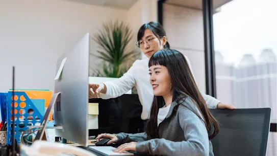 Two businesswomen working at a computer in an office.