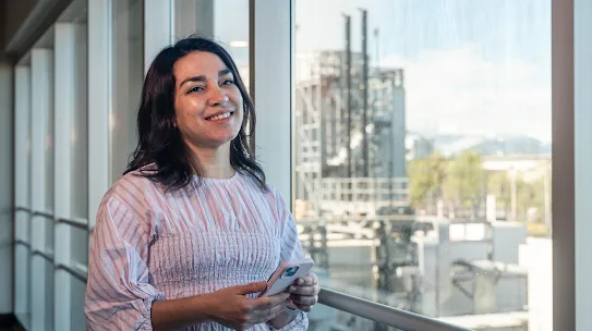 Googler Pia Quiroz smiles with the Quilicura Chile data center in the background outside the windows behind her