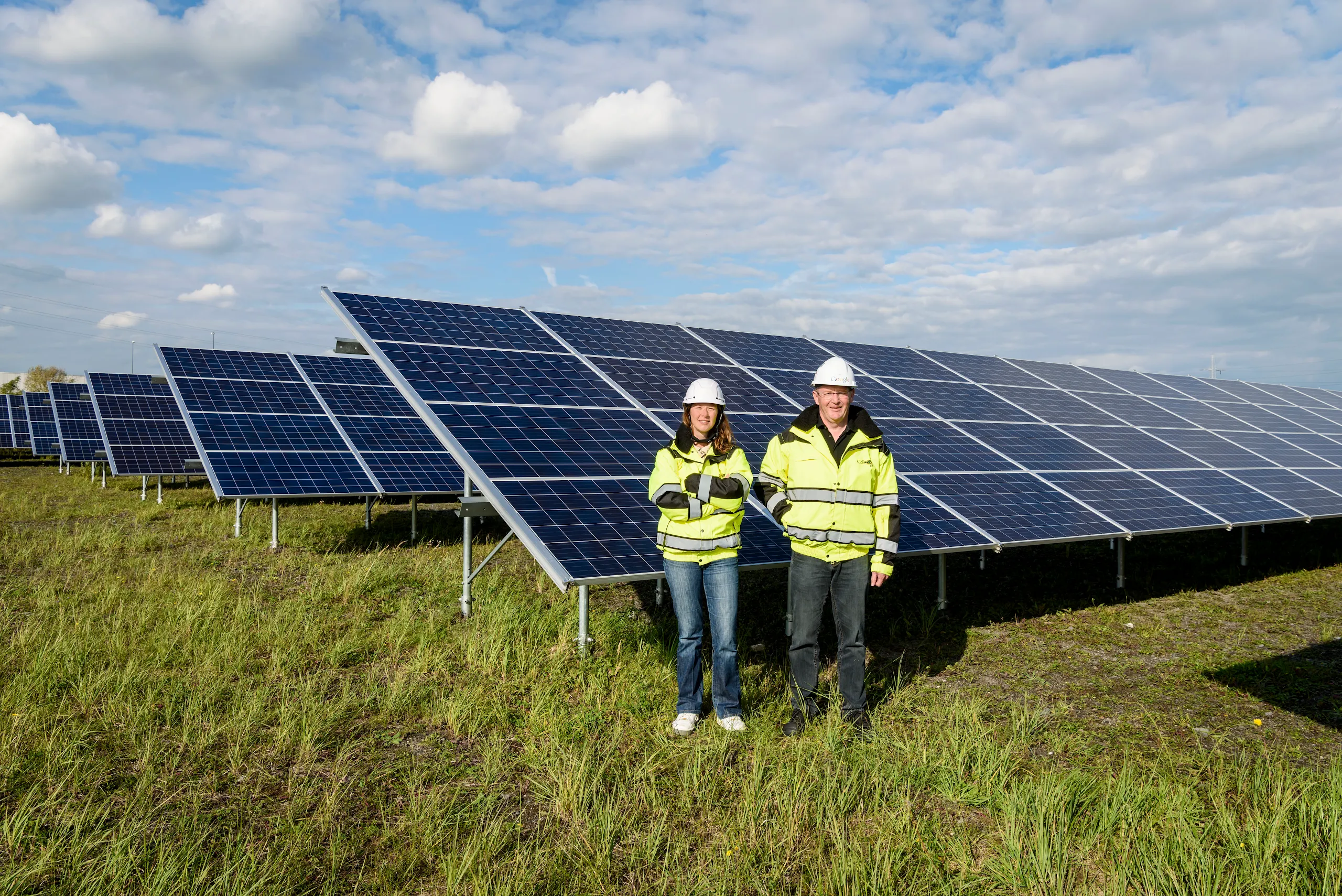 Photograph of two people standing in front of solar panels.