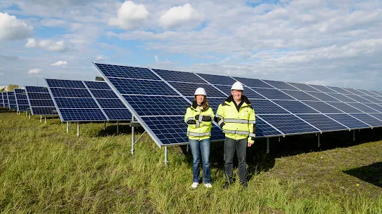 Photograph of two people standing in front of solar panels.