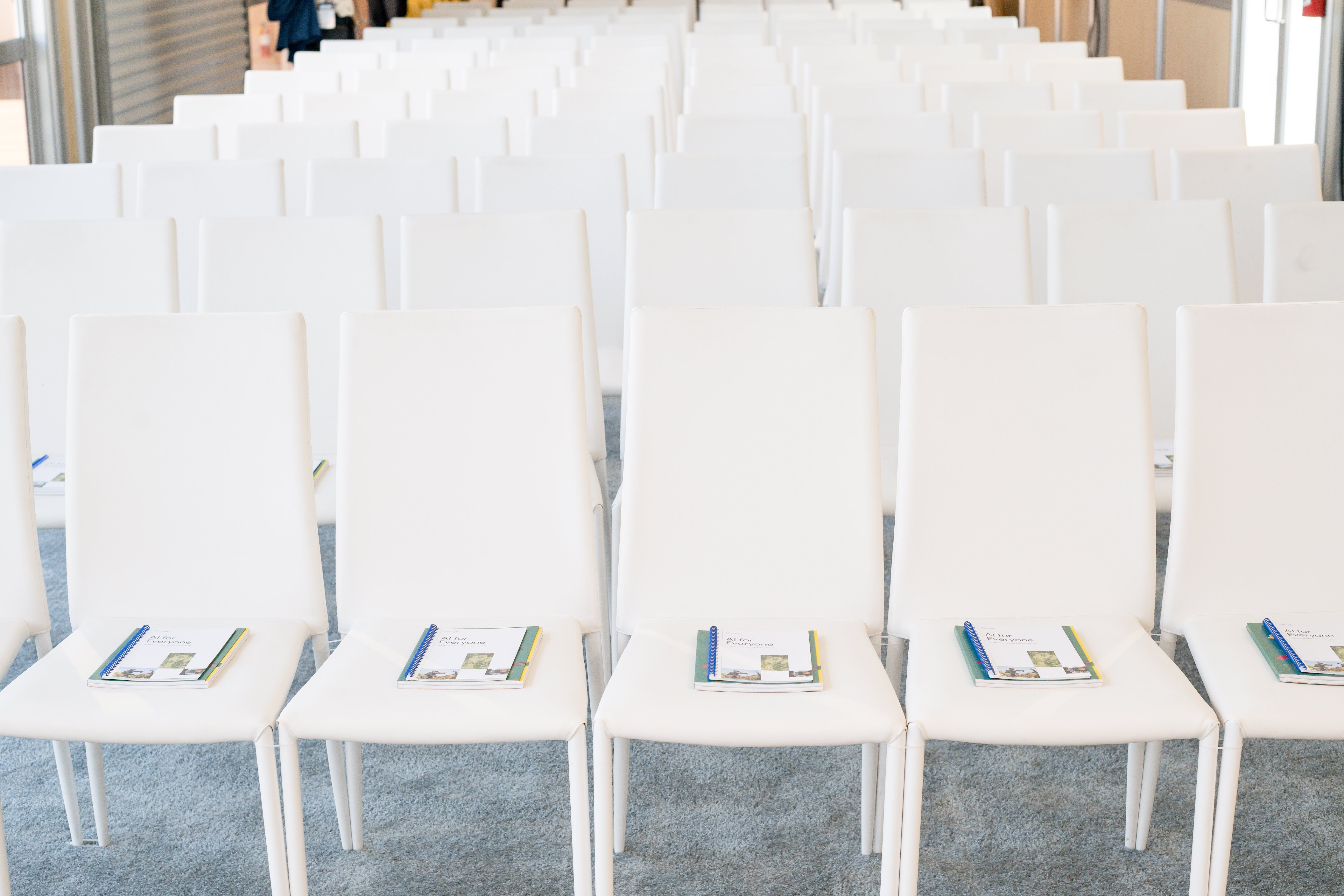 Row of seats set up for an event with a booklet visible on each seat