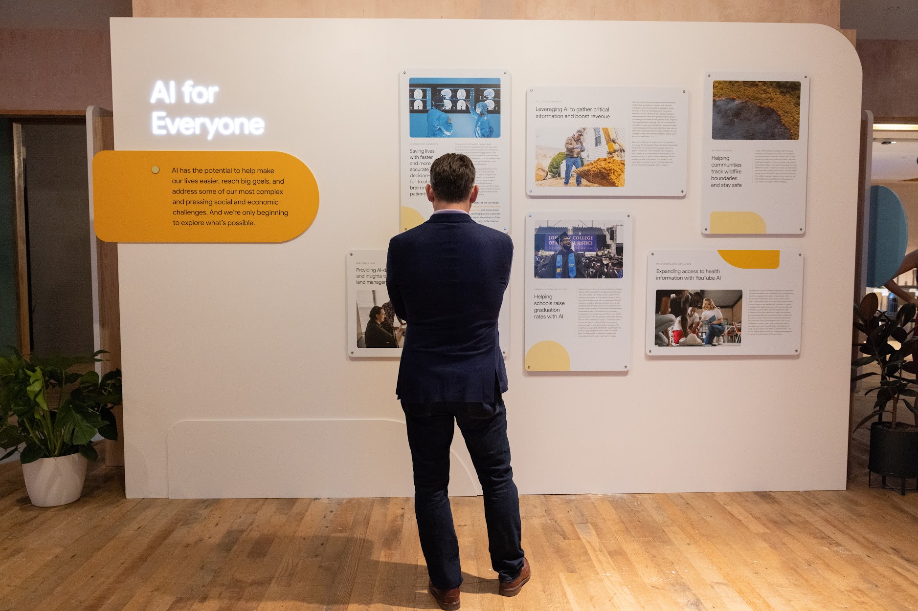 A person standing in front of a display wall reading case studies displayed on the wall