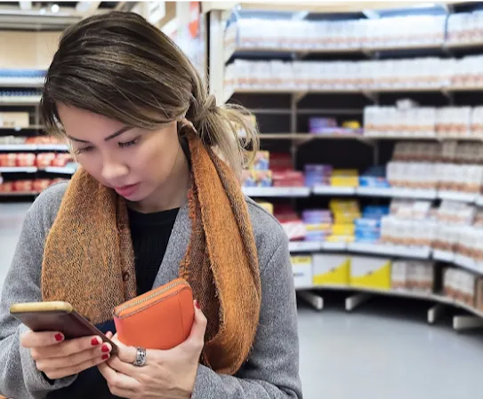 A woman checks the news on her phone while at the store