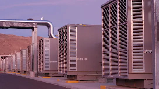 An exterior photograph of backup generators in Storey County, Nevada, data centers at dusk with the Flowery Mountain range in the background.