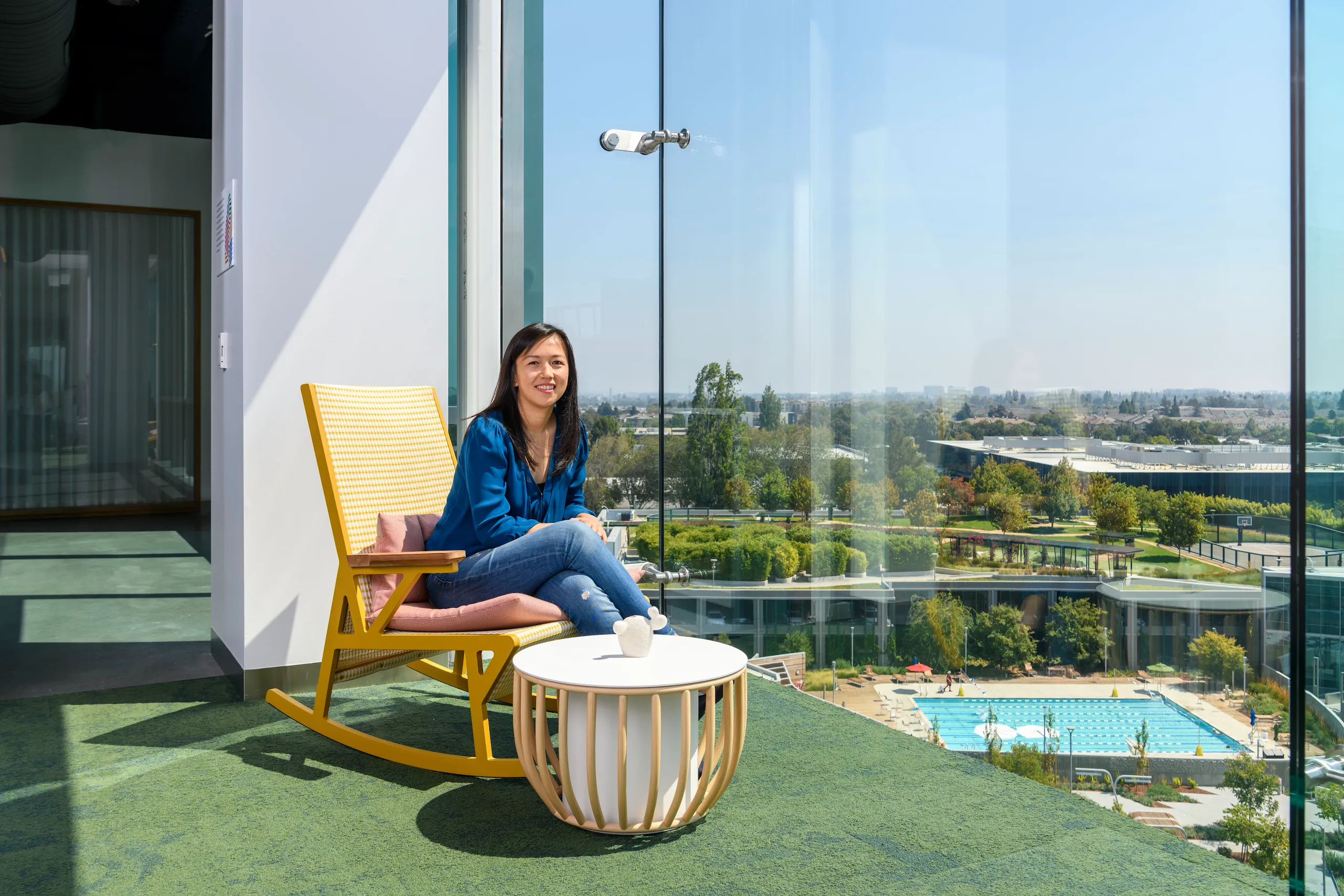 Photograph of a woman sitting on a rocking chair in a sunlit room. 