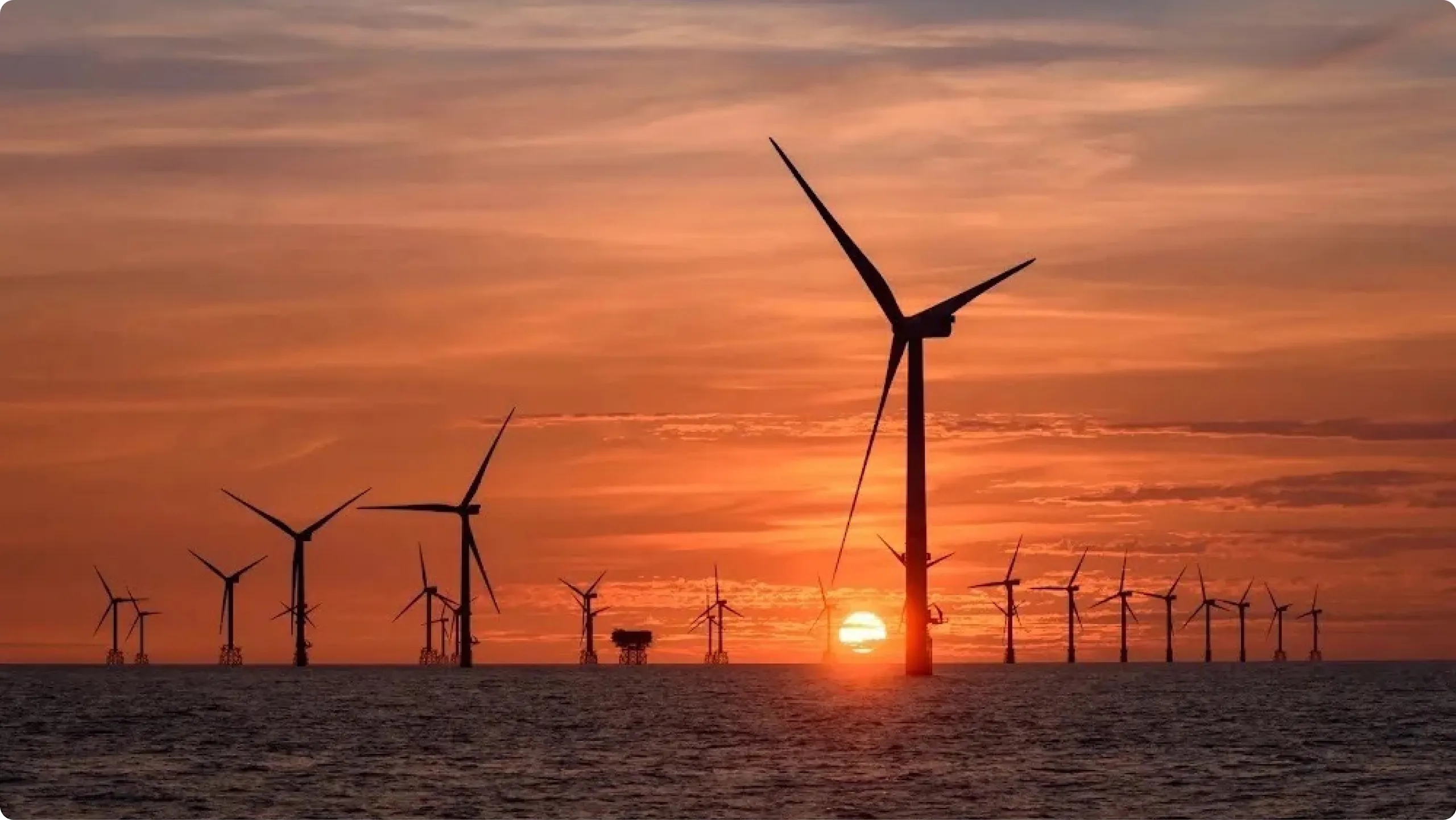 Wind turbines in the sea with the sun setting behind them