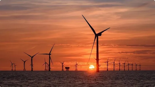 Wind turbines in the sea with the sun setting behind them