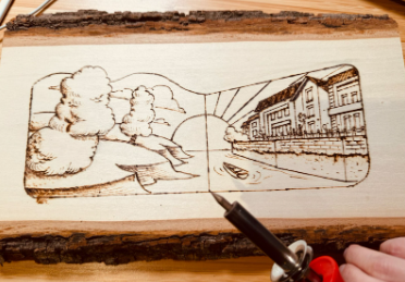 Photograph of a slab of wood with the Doodle artwork sketched on